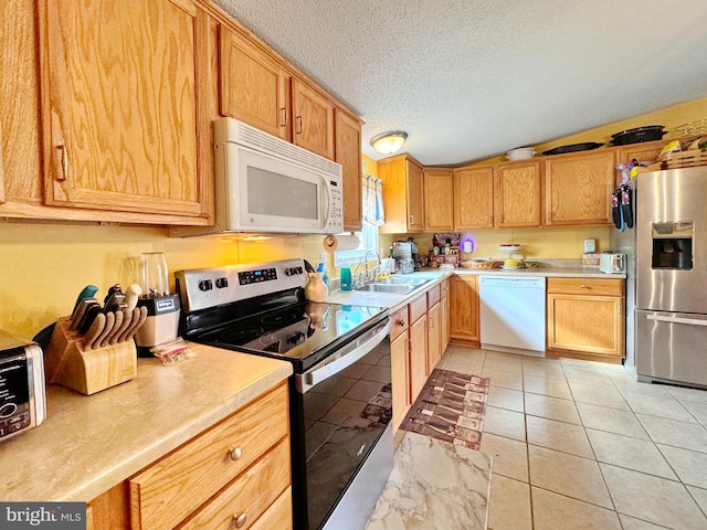 kitchen with light tile patterned flooring, a textured ceiling, stainless steel appliances, and sink