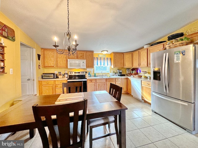 kitchen featuring a textured ceiling, stainless steel appliances, hanging light fixtures, and an inviting chandelier