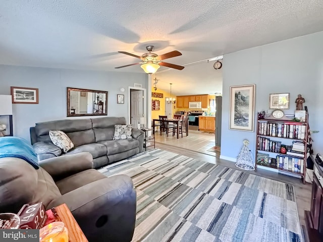 living room with a textured ceiling and ceiling fan with notable chandelier