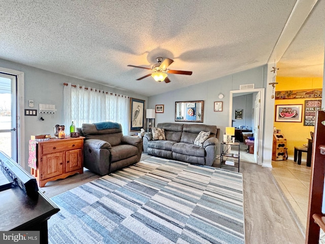 living room with ceiling fan, a textured ceiling, and vaulted ceiling