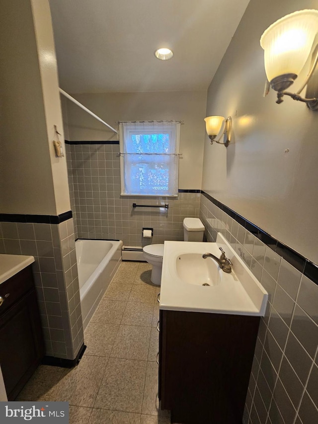 bathroom with vanity, toilet, tile walls, and a baseboard heating unit