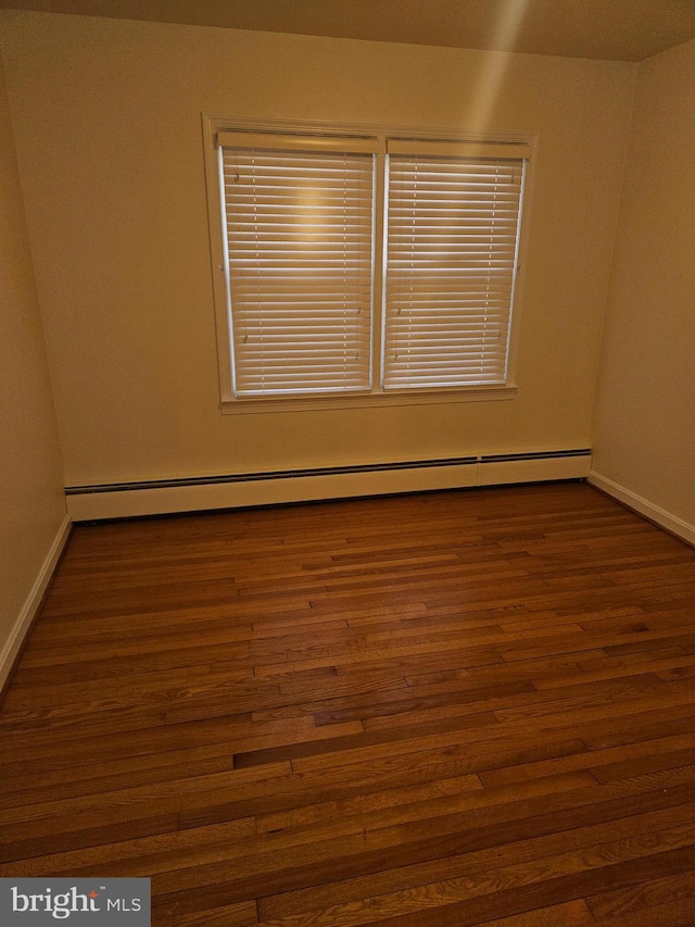 spare room with dark hardwood / wood-style flooring and a baseboard heating unit