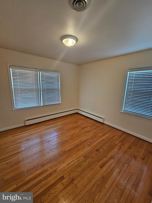 empty room with a baseboard heating unit and hardwood / wood-style flooring