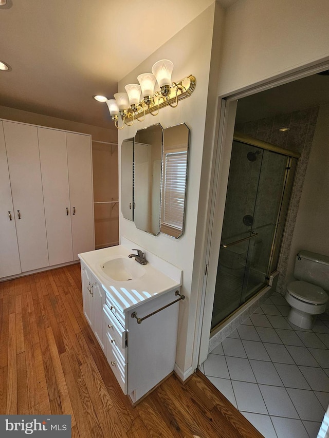 bathroom featuring hardwood / wood-style flooring, vanity, toilet, and a shower with door