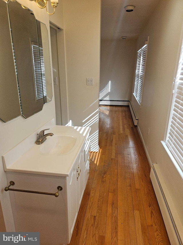 bathroom with hardwood / wood-style flooring, vanity, and a baseboard heating unit