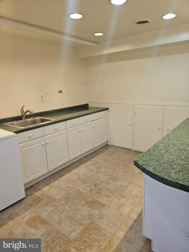 kitchen featuring washer / dryer, white cabinetry, and sink