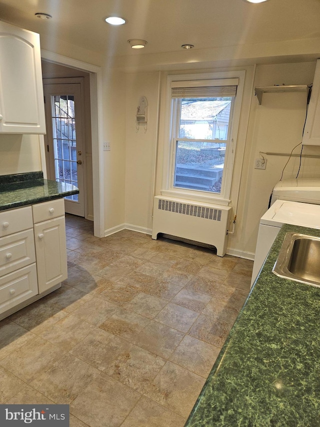 kitchen with white cabinets, radiator heating unit, washer and clothes dryer, and sink