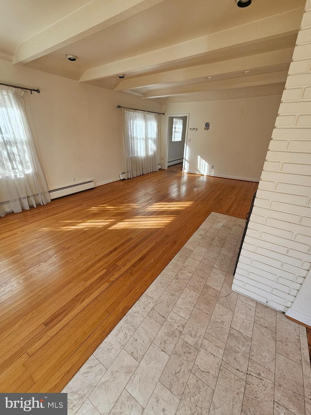 empty room featuring beam ceiling, light hardwood / wood-style flooring, and baseboard heating