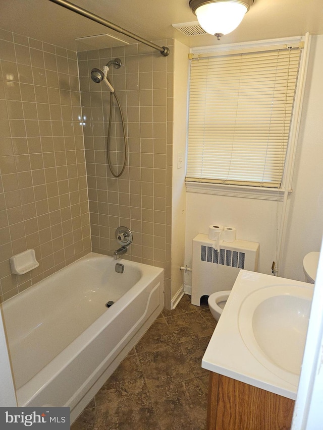 full bathroom with tiled shower / bath combo, toilet, vanity, and radiator