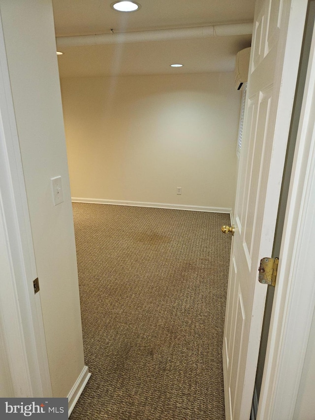 unfurnished room featuring an AC wall unit and dark carpet