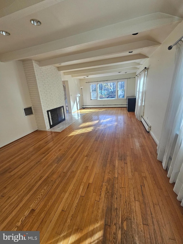 unfurnished living room with beamed ceiling, wood-type flooring, a brick fireplace, and a baseboard heating unit