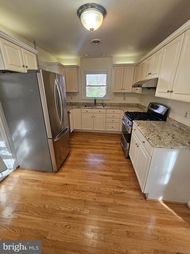 kitchen with white cabinetry, stainless steel appliances, and light wood-type flooring