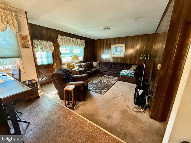 carpeted living room with wooden walls