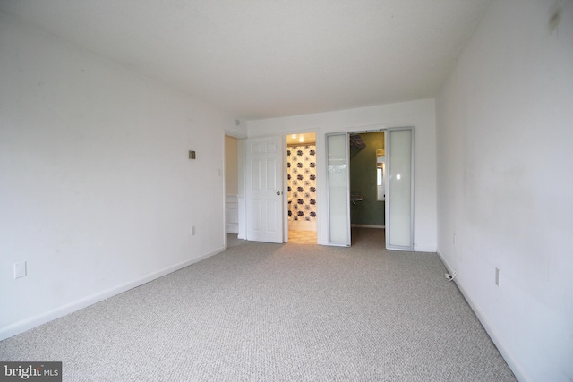 unfurnished bedroom with a spacious closet, light carpet, and connected bathroom