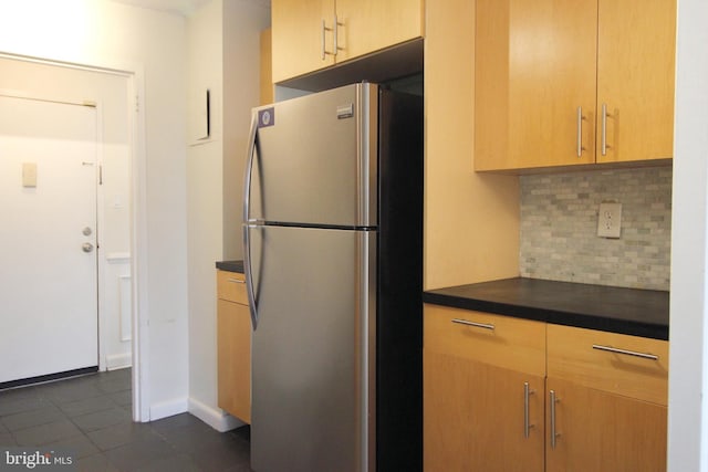 kitchen featuring decorative backsplash, stainless steel fridge, light brown cabinets, and dark tile patterned flooring