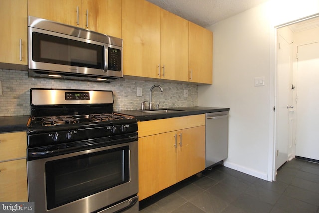 kitchen featuring stainless steel appliances, dark tile patterned flooring, tasteful backsplash, and sink