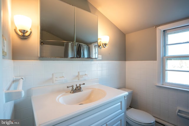 bathroom featuring vanity, lofted ceiling, a shower with curtain, toilet, and tile walls