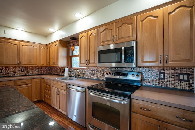 kitchen featuring backsplash, dark stone counters, stainless steel appliances, sink, and hardwood / wood-style floors