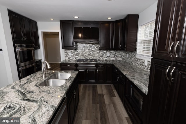 kitchen featuring sink, light stone counters, dark hardwood / wood-style flooring, stainless steel appliances, and decorative backsplash