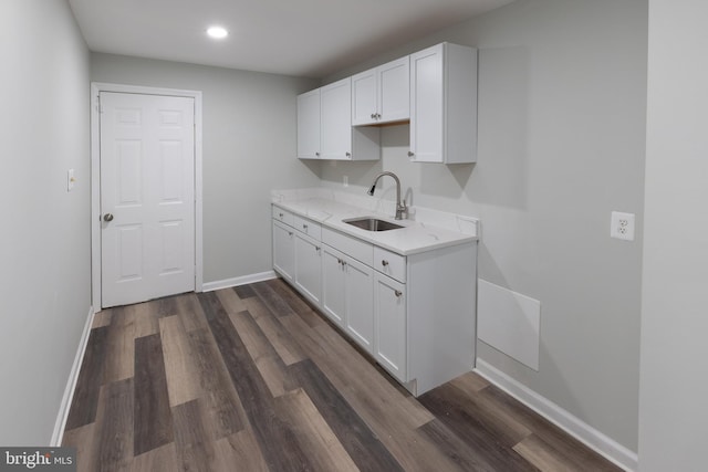 kitchen featuring dark wood-type flooring, light stone countertops, sink, and white cabinets