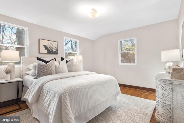 bedroom with dark hardwood / wood-style floors, vaulted ceiling, and multiple windows