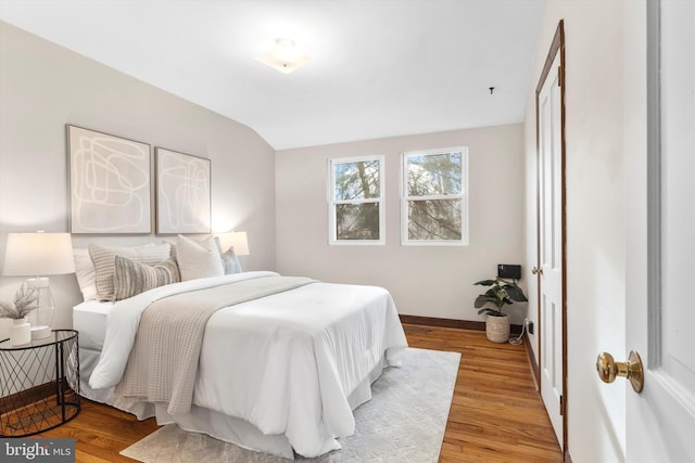 bedroom with light wood-type flooring and vaulted ceiling