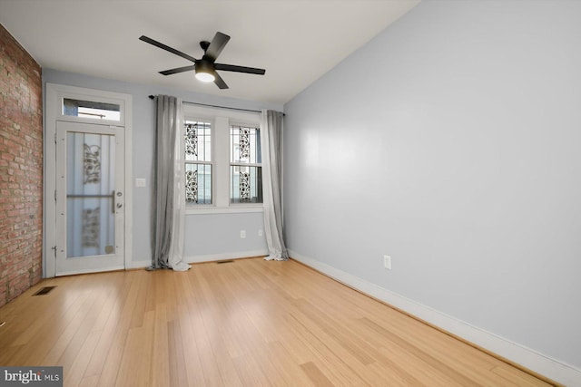 unfurnished room with ceiling fan, light hardwood / wood-style flooring, and brick wall