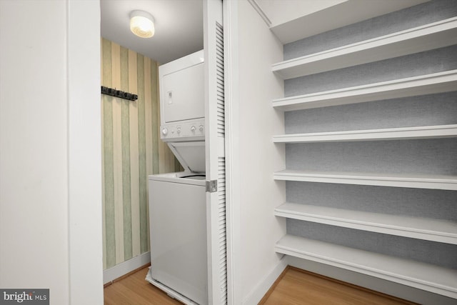 laundry room with hardwood / wood-style floors and stacked washer and dryer