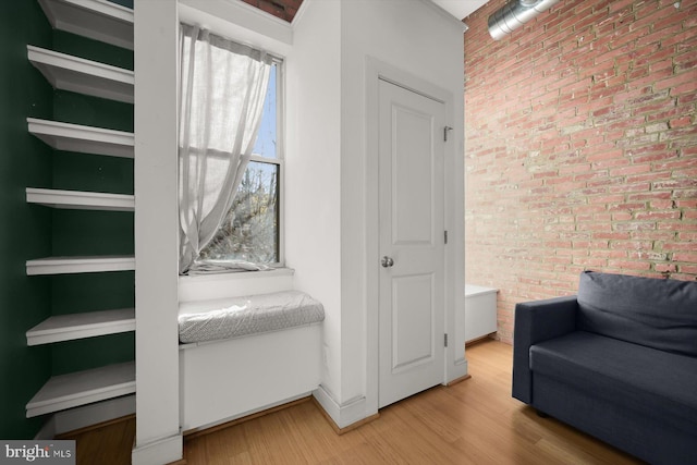 living area with hardwood / wood-style flooring and brick wall