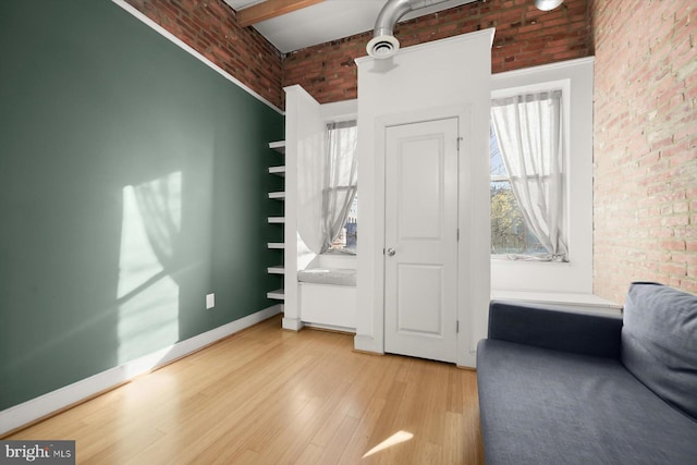 living area featuring brick wall, a high ceiling, and wood-type flooring