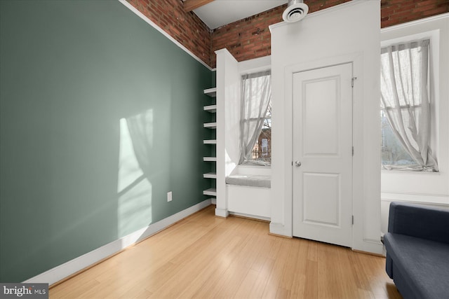 bedroom with brick wall and light wood-type flooring