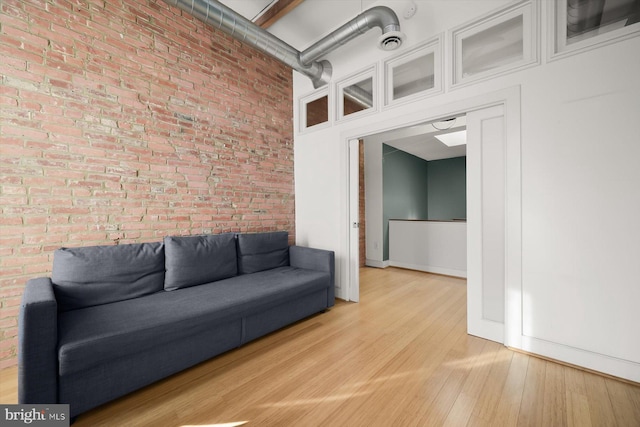 unfurnished living room featuring light hardwood / wood-style flooring and brick wall