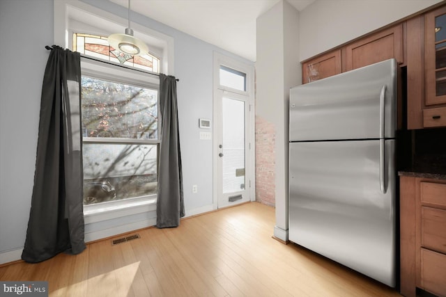 kitchen with stainless steel fridge, light hardwood / wood-style flooring, and hanging light fixtures