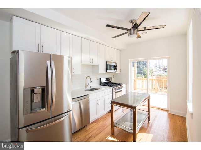 kitchen with white cabinets, light hardwood / wood-style floors, sink, and appliances with stainless steel finishes