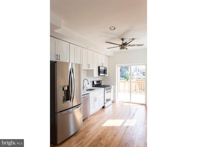 kitchen featuring decorative backsplash, appliances with stainless steel finishes, light wood-type flooring, ceiling fan, and white cabinetry