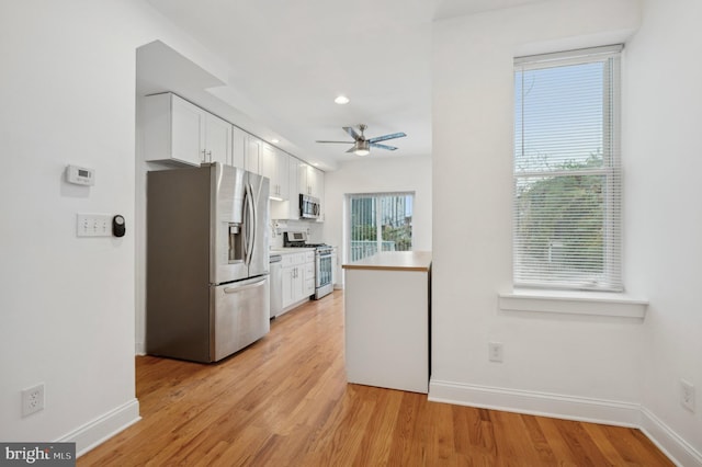 kitchen with white cabinets, ceiling fan, light hardwood / wood-style floors, and appliances with stainless steel finishes