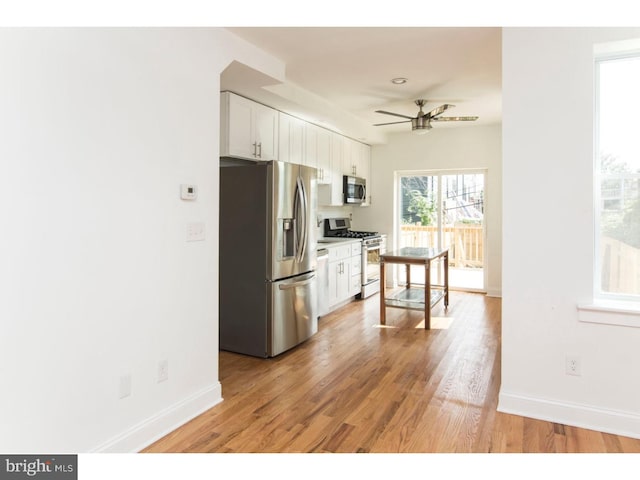 kitchen featuring ceiling fan, light hardwood / wood-style floors, white cabinetry, and stainless steel appliances