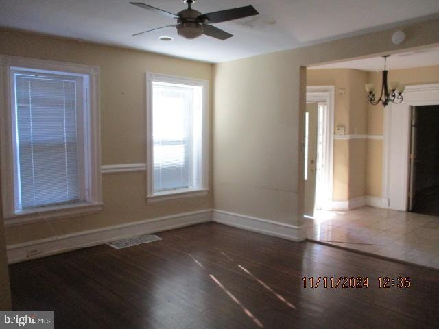 empty room featuring hardwood / wood-style floors and ceiling fan with notable chandelier