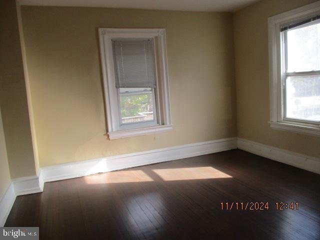 unfurnished room featuring dark wood-type flooring and a healthy amount of sunlight