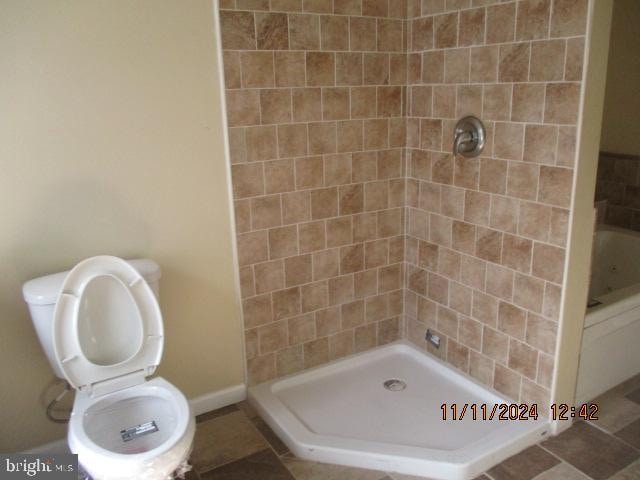 bathroom featuring a tile shower and toilet