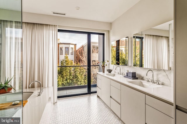 bathroom with double vanity, backsplash, a sink, and visible vents