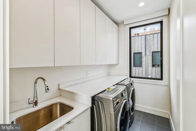 washroom featuring cabinet space, a sink, separate washer and dryer, dark tile patterned flooring, and baseboards