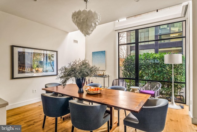 dining space with light wood-type flooring, visible vents, and baseboards