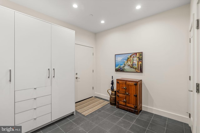 interior space with baseboards, dark tile patterned flooring, and recessed lighting