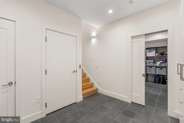 below grade area with dark tile patterned flooring, stairway, recessed lighting, and baseboards