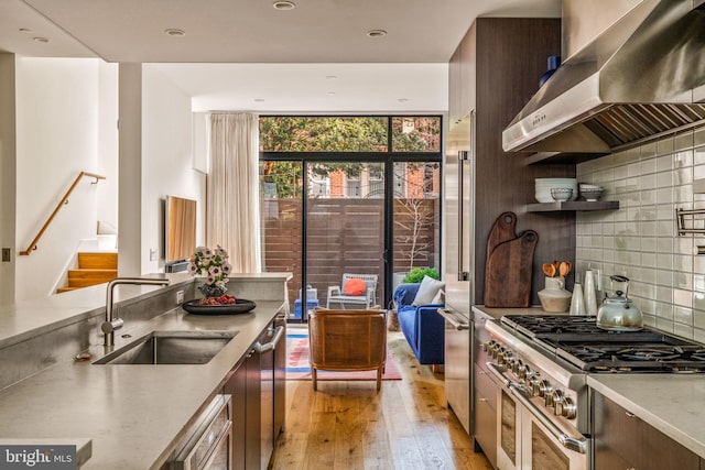 kitchen with a sink, exhaust hood, high quality appliances, light countertops, and floor to ceiling windows