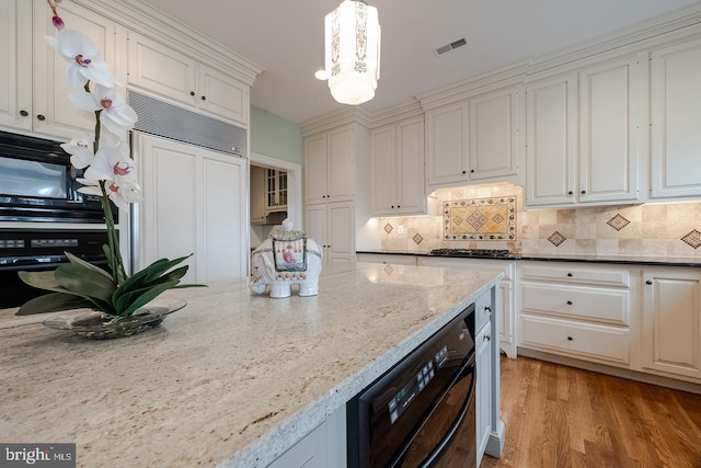 kitchen featuring light stone counters, decorative light fixtures, decorative backsplash, black appliances, and light wood-type flooring