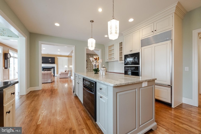 kitchen with black appliances, white cabinetry, hanging light fixtures, and light hardwood / wood-style flooring