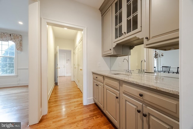 kitchen with light stone counters, sink, and light hardwood / wood-style floors