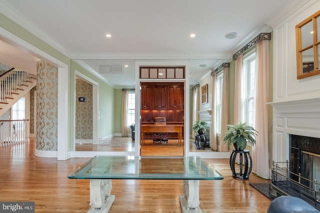 exercise room with light hardwood / wood-style floors, a premium fireplace, and crown molding